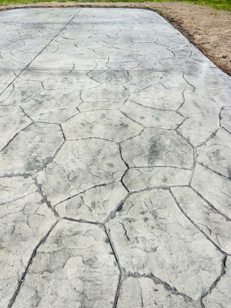 A close up of a stamped concrete driveway with a stone pattern.