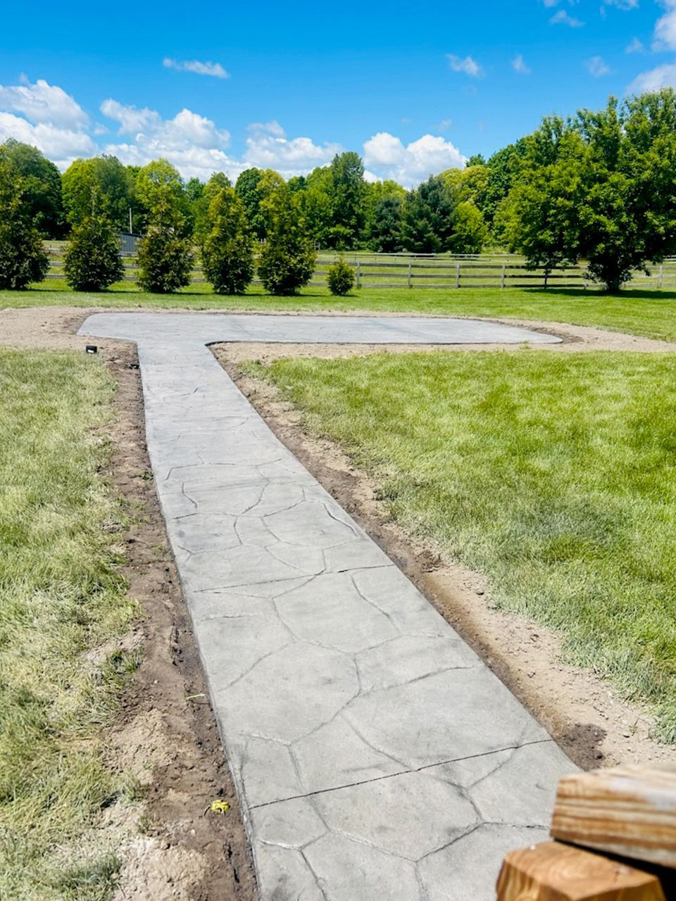 A stamped concrete walkway is being built in a grassy field.