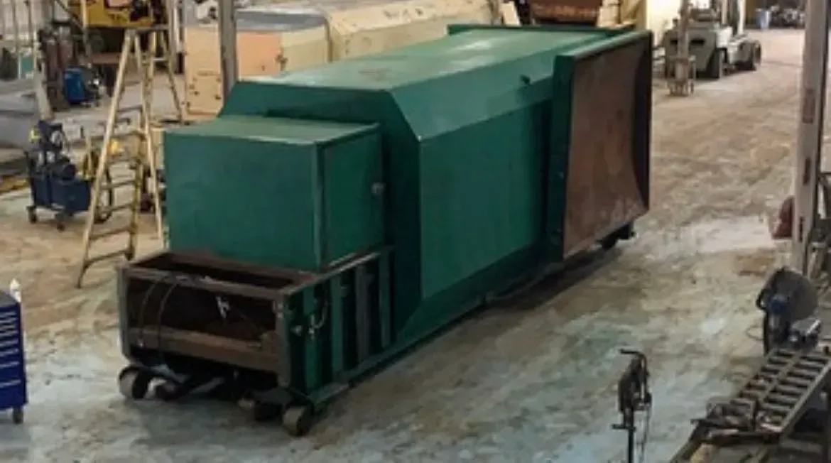 Green industrial machine on wheels in a workshop setting.
