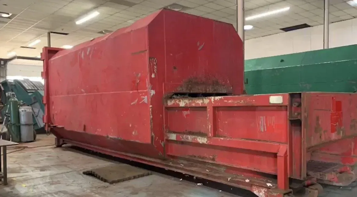 Red industrial baler inside a building.