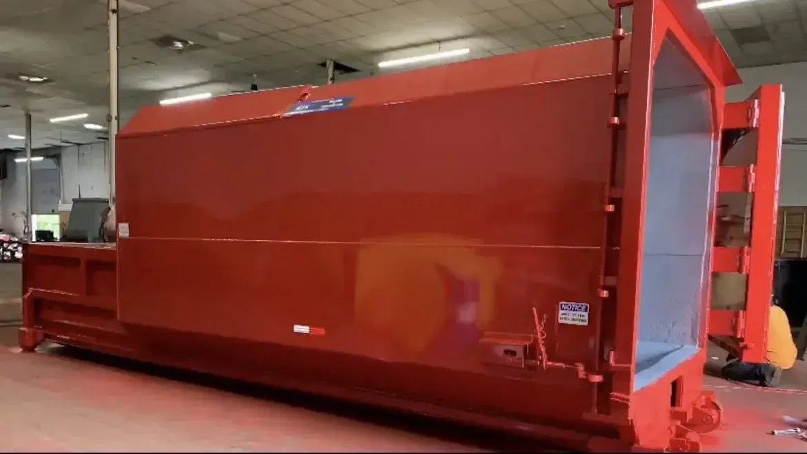 Large red industrial waste compactor unit.