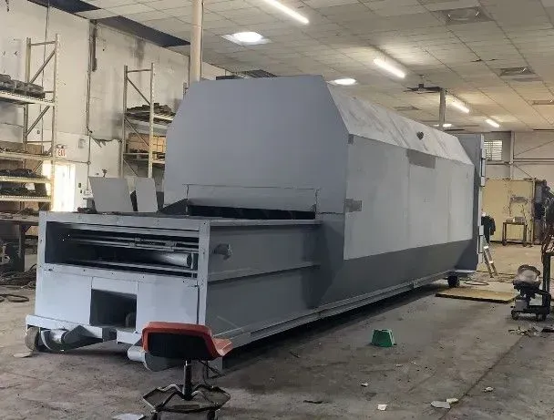 Large, gray industrial machine in a workshop, possibly a conveyor, on wheels.