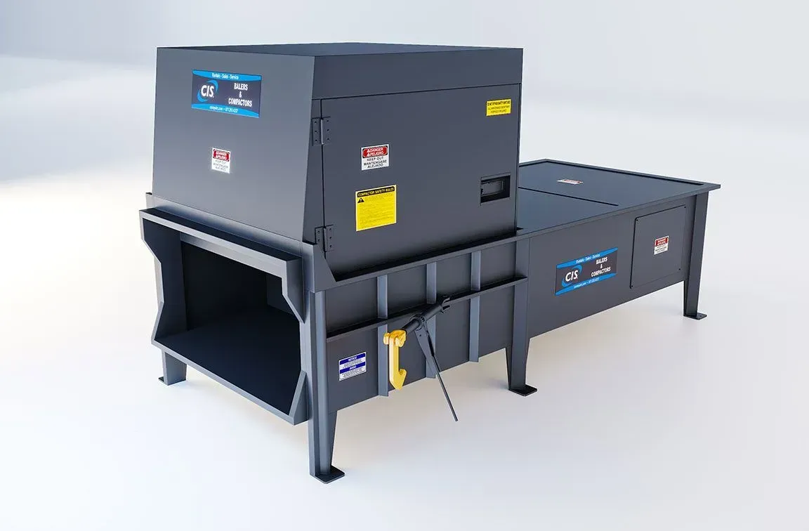 Green crane loading metal cylinder into a container. Industrial setting, orange and white buildings in background.