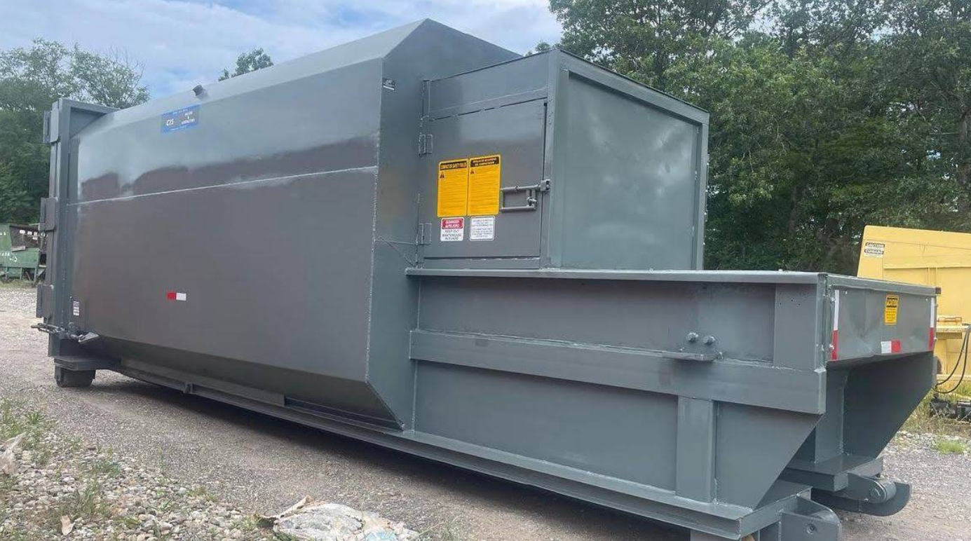 Gray garbage compactor truck parked outdoors.