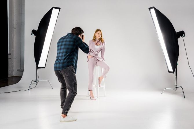 Photographer taking photo of a model in a studio with two softbox lights.
