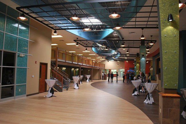 A large hallway with tables and people walking through it.