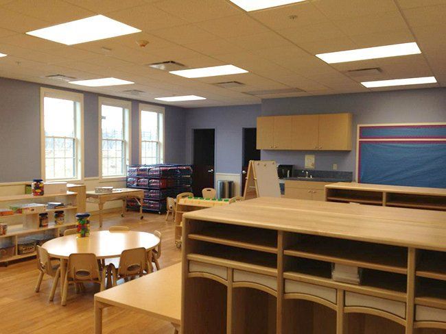 A classroom with tables and chairs and a blue board.