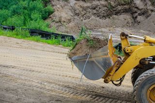 A bulldozer is loading dirt into a bucket on a dirt road.