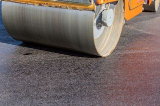 A roller is rolling asphalt on a road.