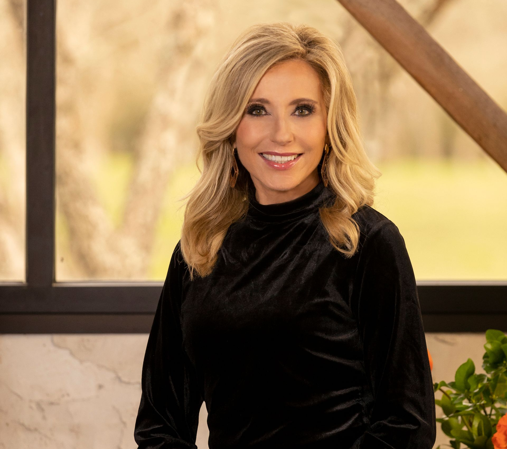 A woman wearing a blue sweater and a blue scarf is smiling for the camera.