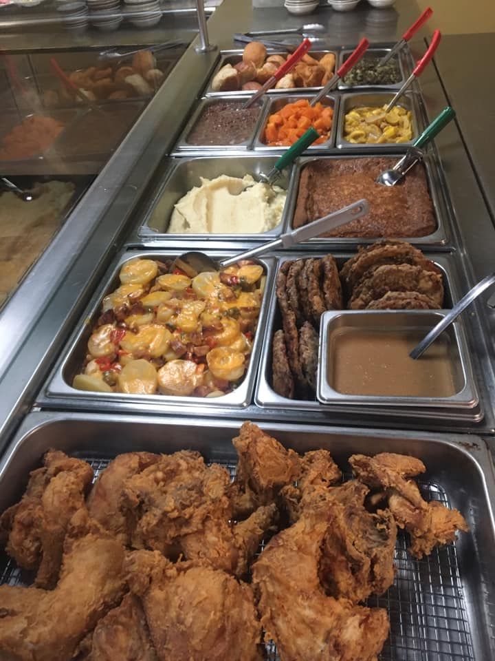 A buffet with fried chicken, mashed potatoes, vegetables, and gravy.