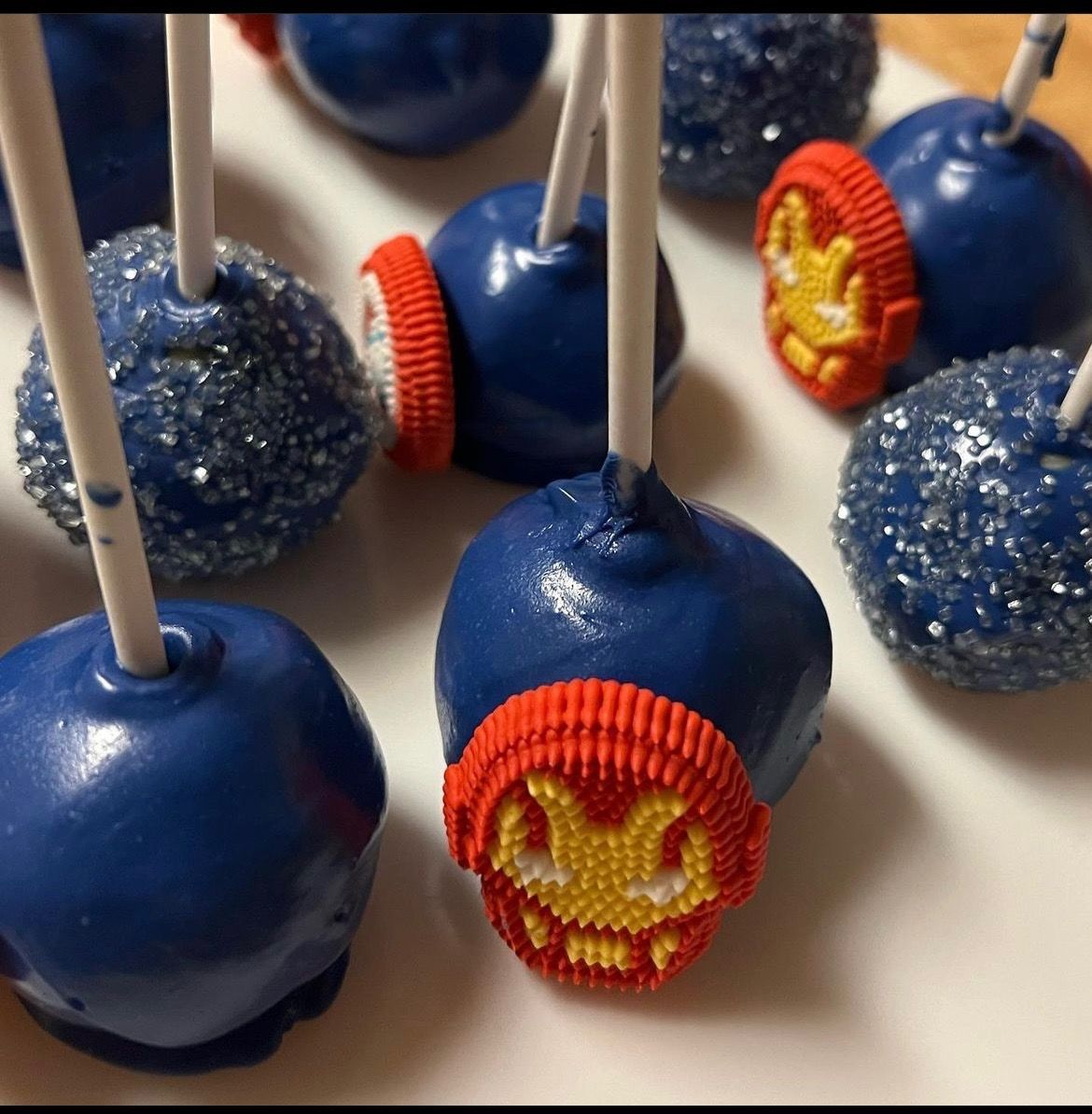 A bunch of blue cake pops with a face on them