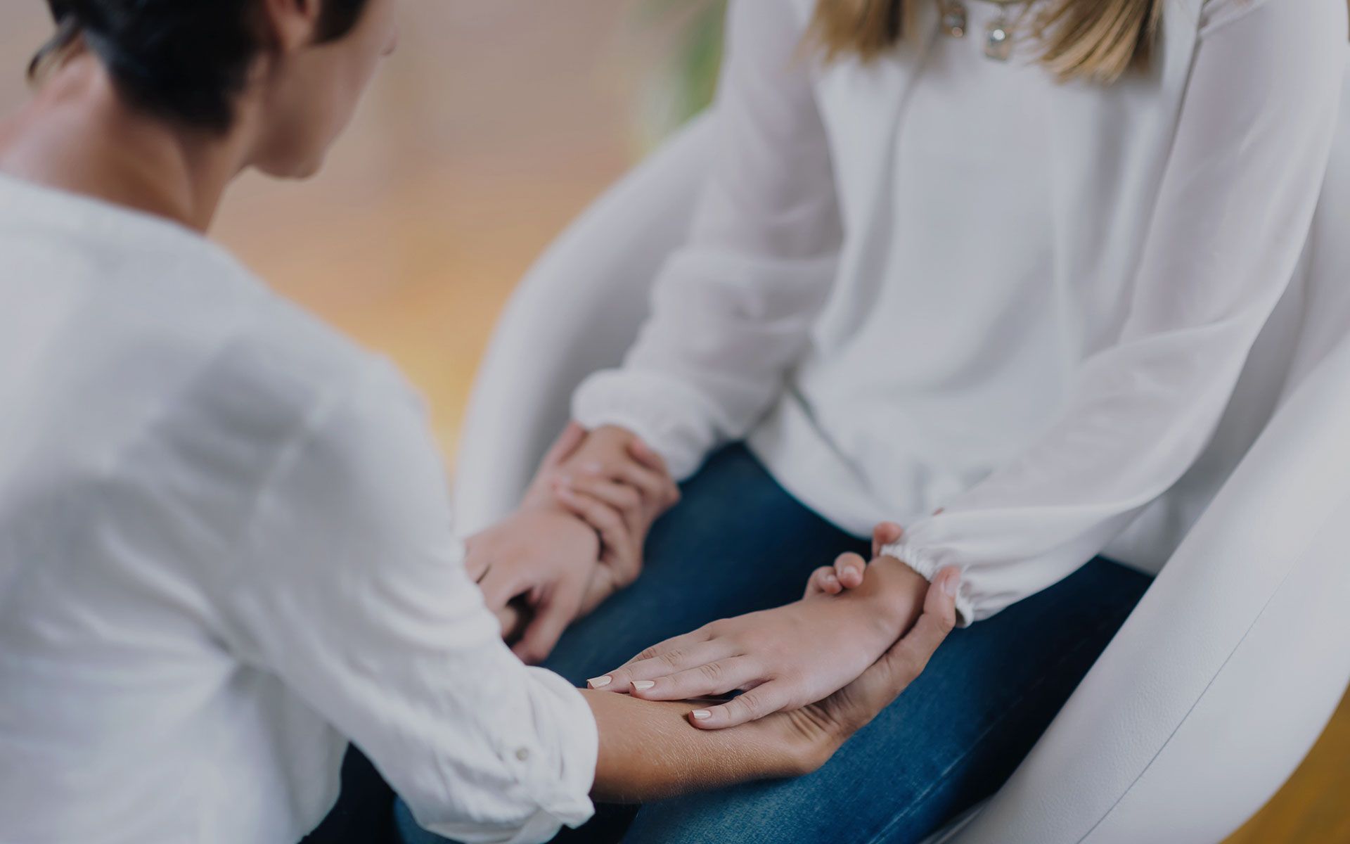 A woman is holding another woman 's hand while sitting in a chair.