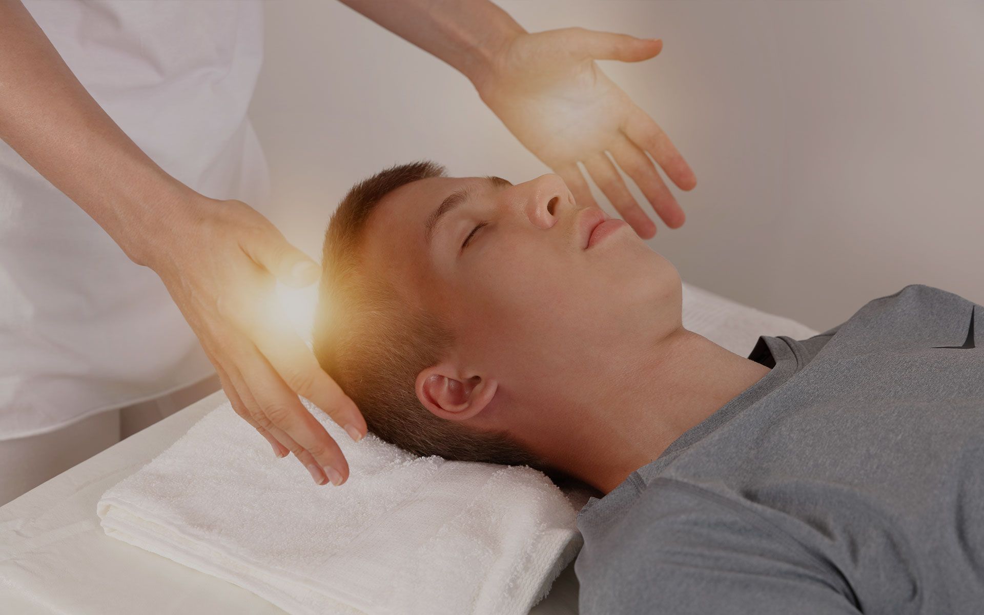 A man is laying on a bed getting a healing session.