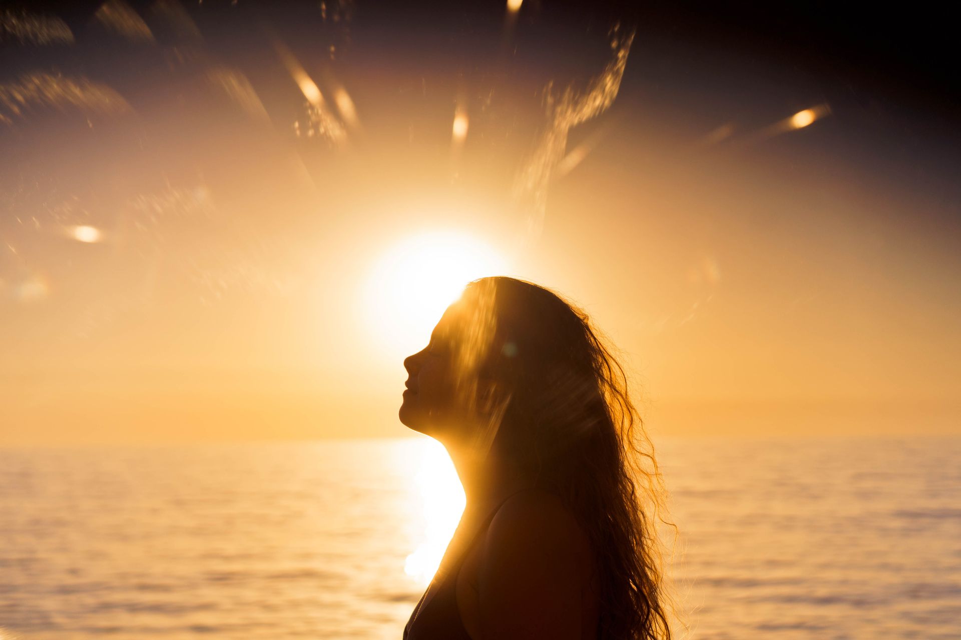 A woman is praying with her hands folded in front of her face.