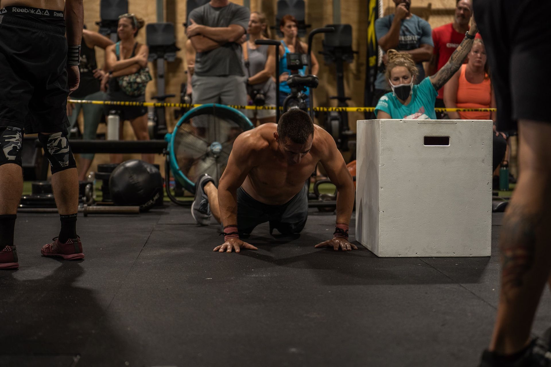 Athlete doing push-ups beside a white plyo box in a crowded gym at the best crossfit gym in Fort Walton Beach, FL