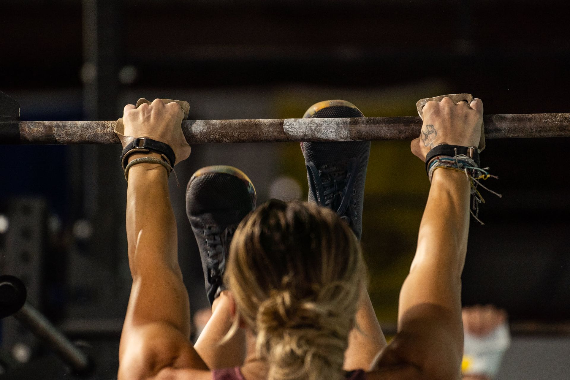 Person doing a pull-up on a bar in a gym, seen from behind at the best crossfit gym in Fort Walton Beach, FL