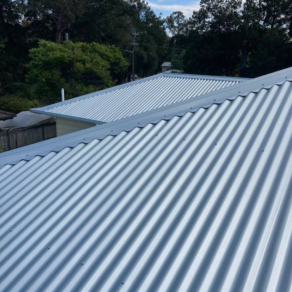 A Close Up of a Metal Roof With Trees in the Background — Richmond River Roofing Pty Ltd in Northern Rivers, NSW
