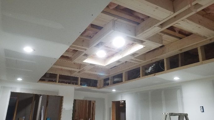 Interior construction with recessed lighting; exposed wooden beams, drywall, and illuminated fixtures.
