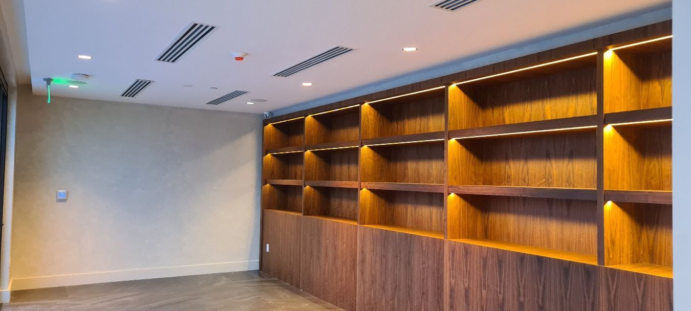 Empty room with wooden shelves illuminated by recessed lighting.