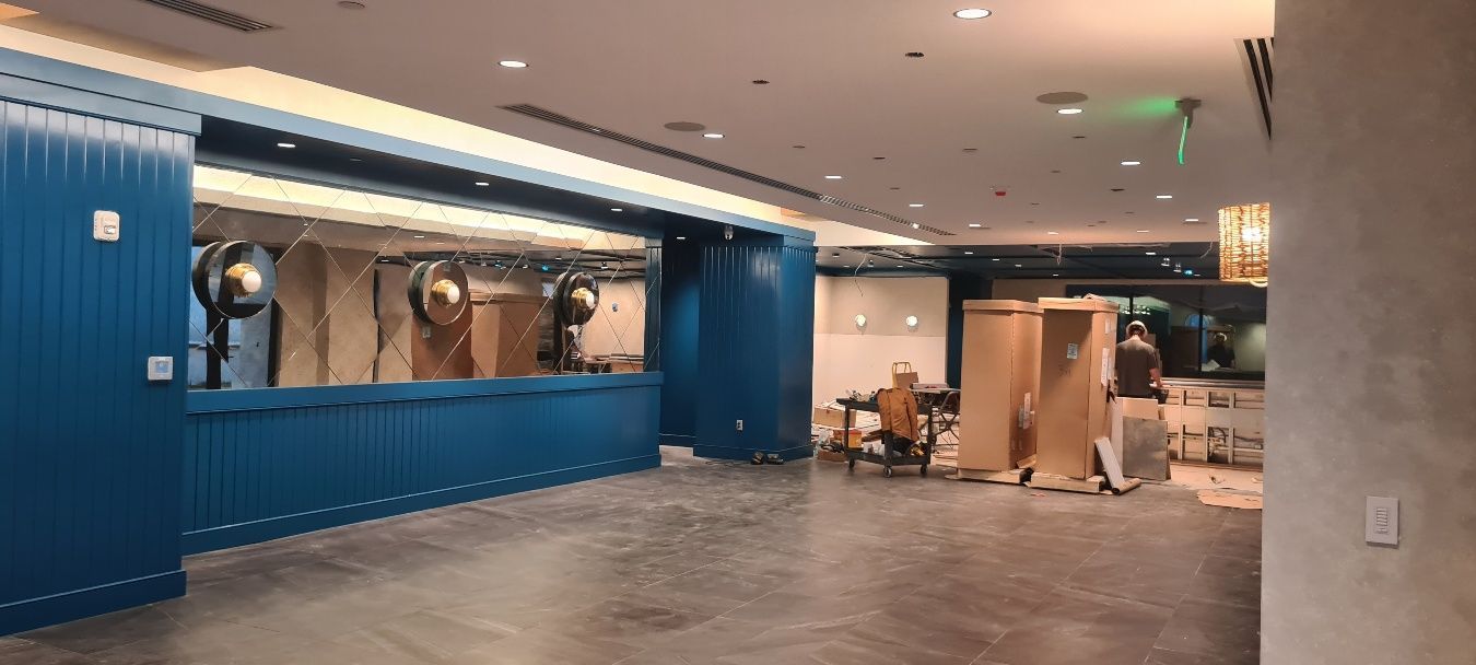 A large, empty blue counter area in a new building under construction, with boxes and debris in the background.
