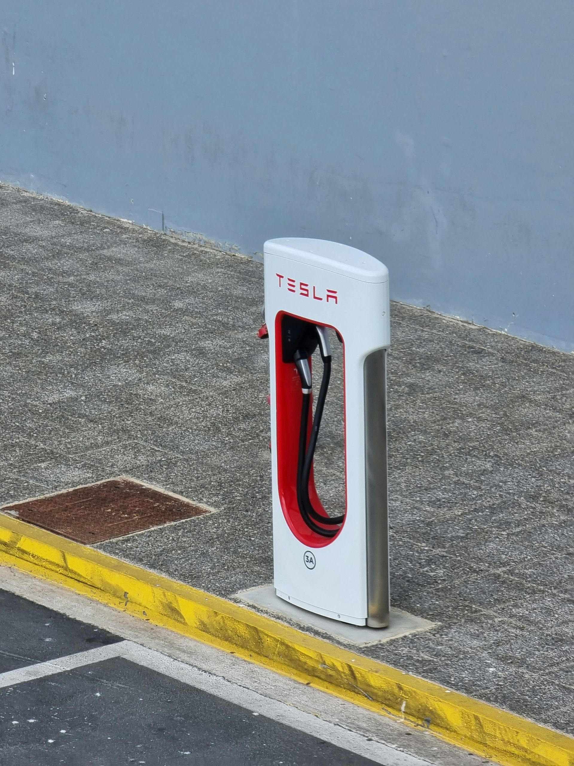 Tesla charging station with a red and white design on concrete.