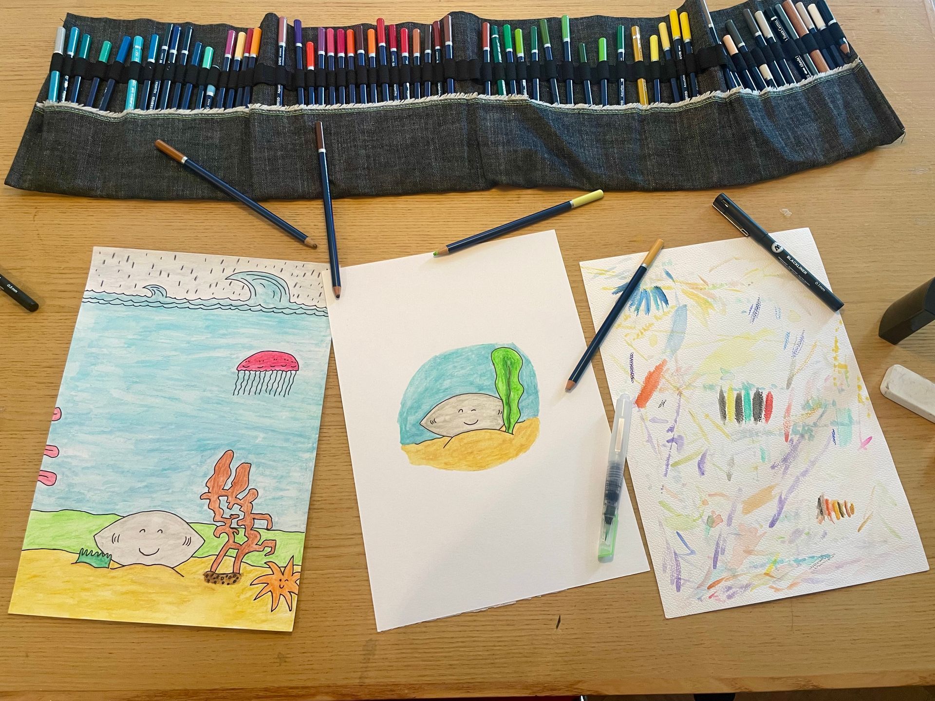 Kleurpotloden, tekeningen van strandgezichten en abstracte kunst op een tafel.