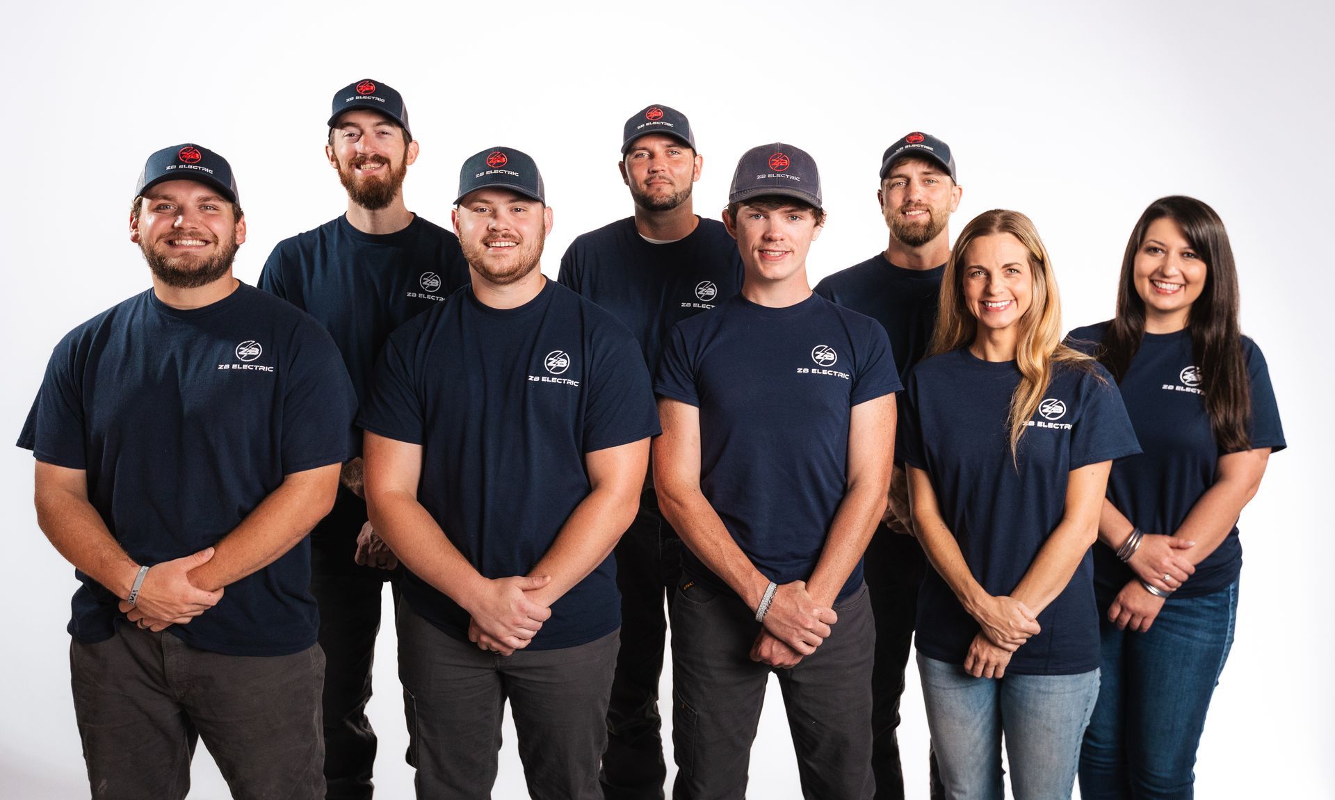 A group of people wearing blue shirts and hats are posing for a picture.