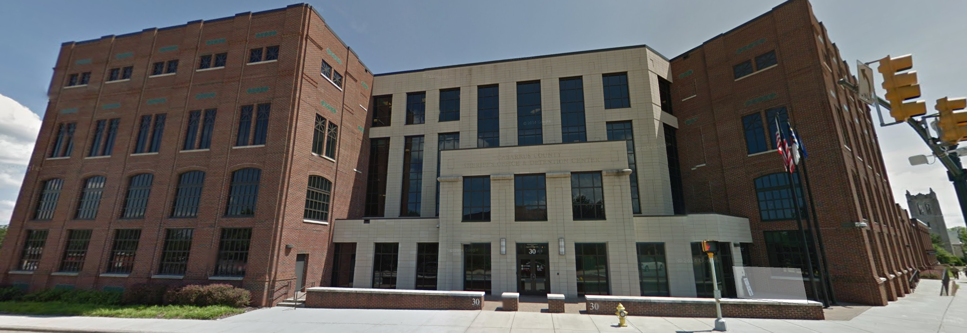 A large brick building with a lot of windows is sitting on the corner of a street.