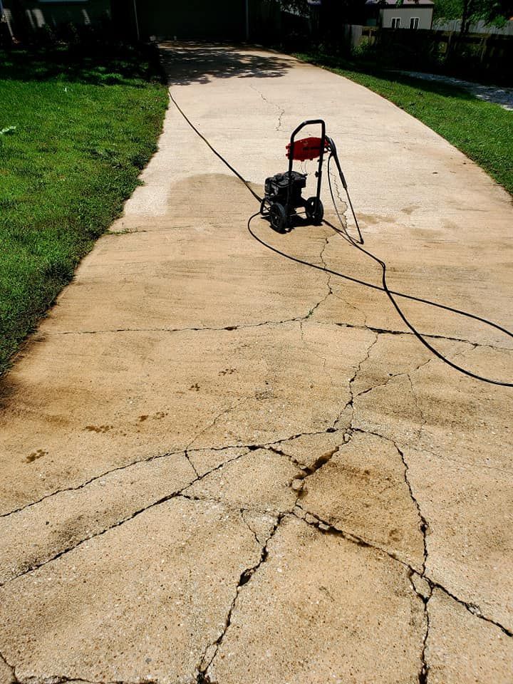 A man is standing on a ladder painting the side of a white house.
