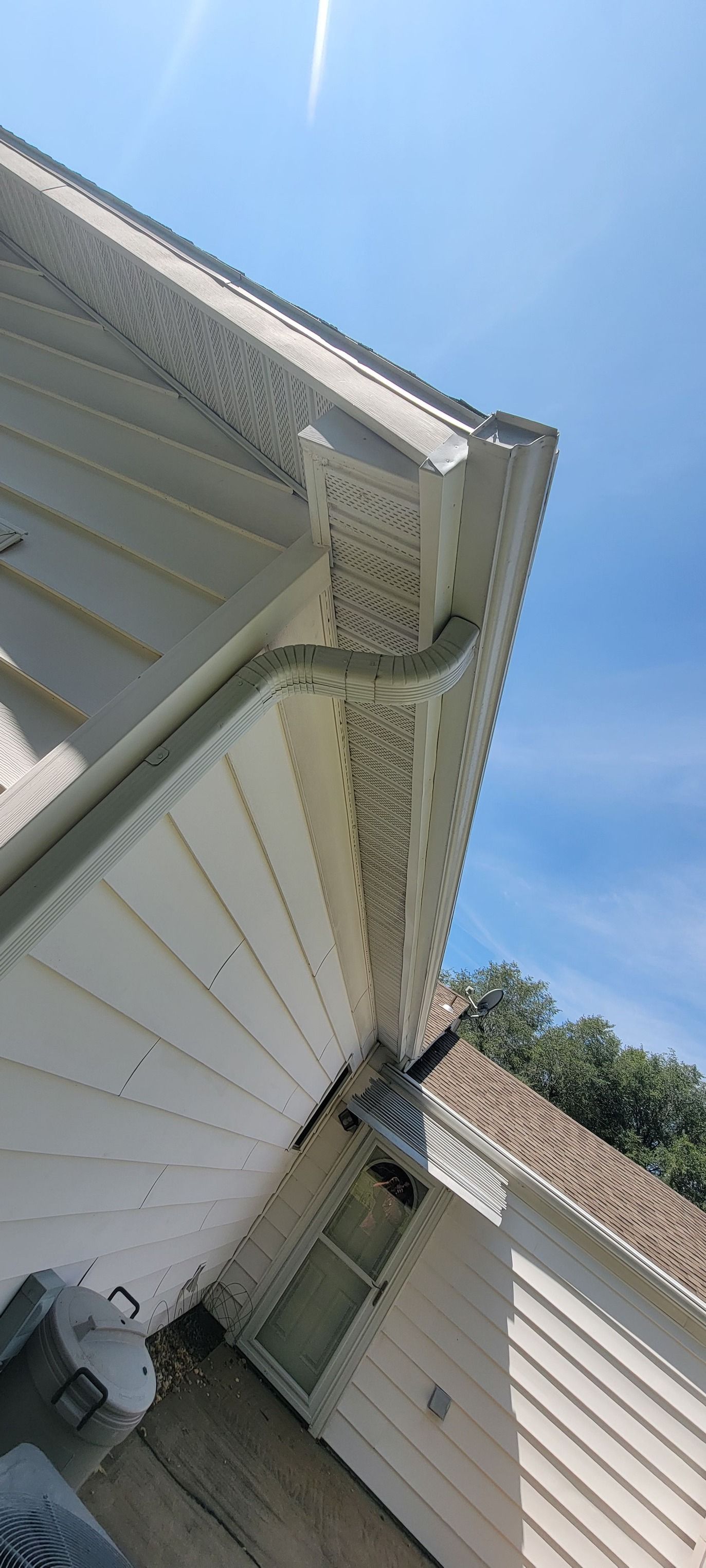 A white house with a gutter on the side of it.