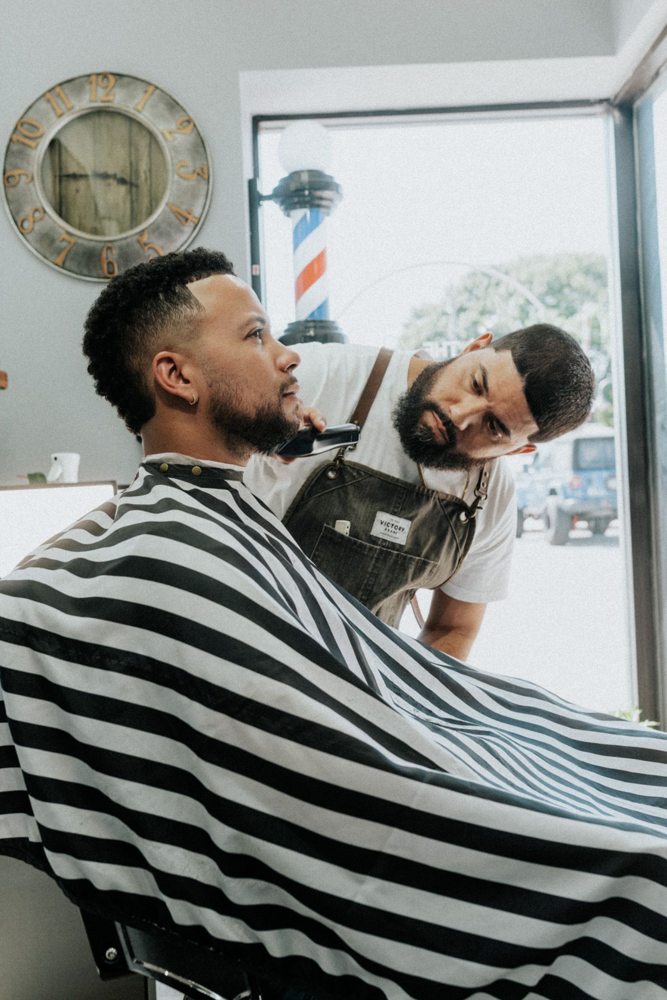 Barber trims a man’s beard with attention to his oval face shape at a barbershop in Long Branch NJ