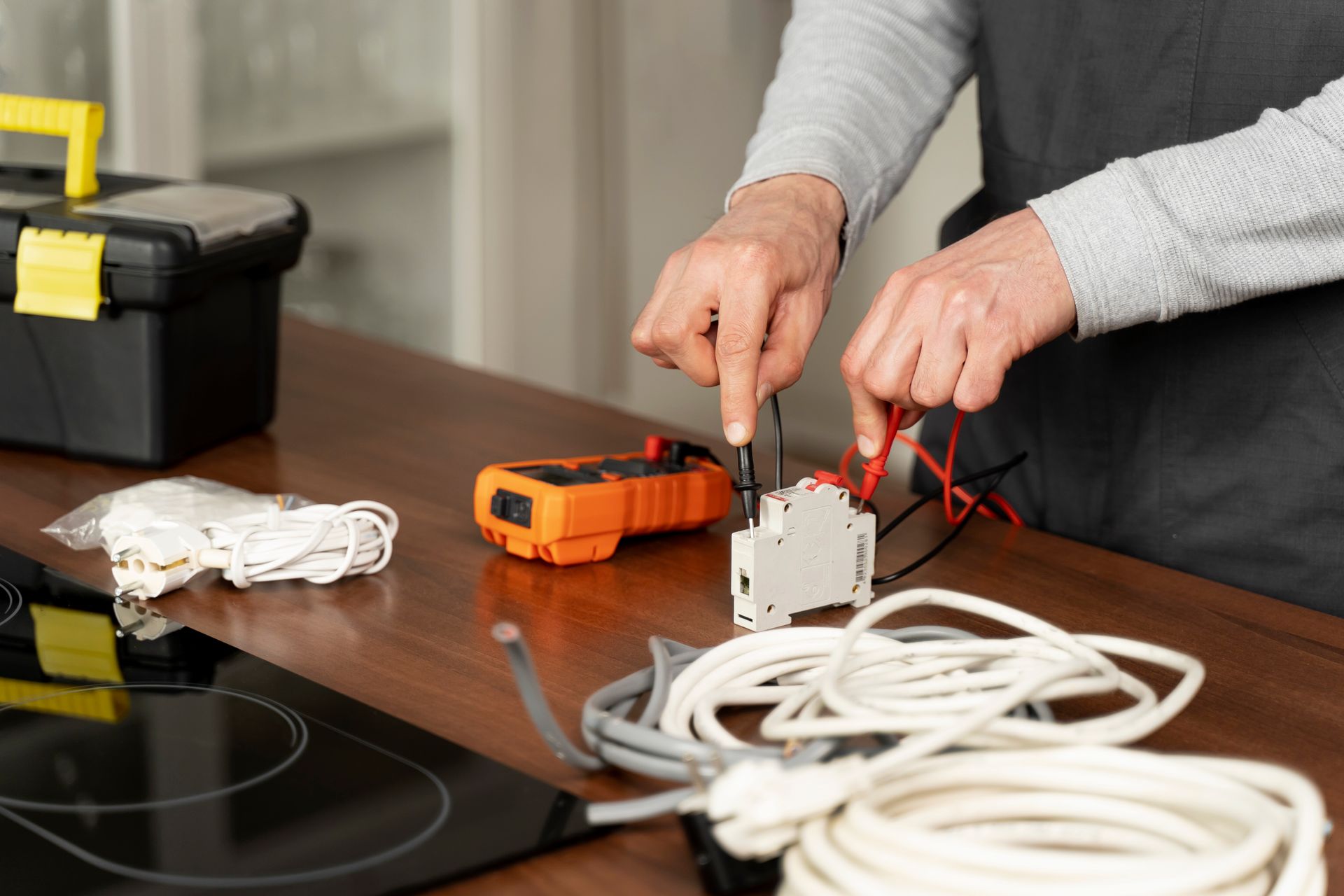 A person is sitting at a table working on electrical wires.
