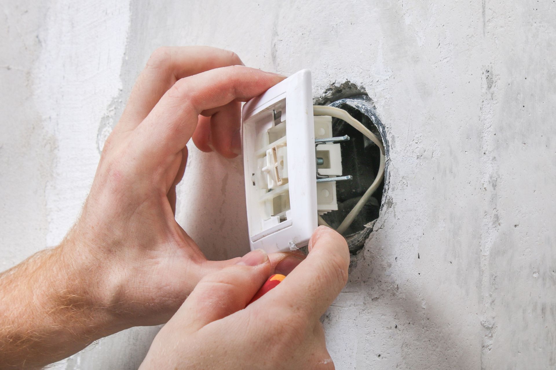 A person is installing a light switch on a wall.