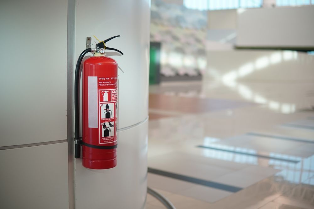 Red Fire Extinguisher Mounted on A White Wall — Elibon Solutions in Garbutt, QLD