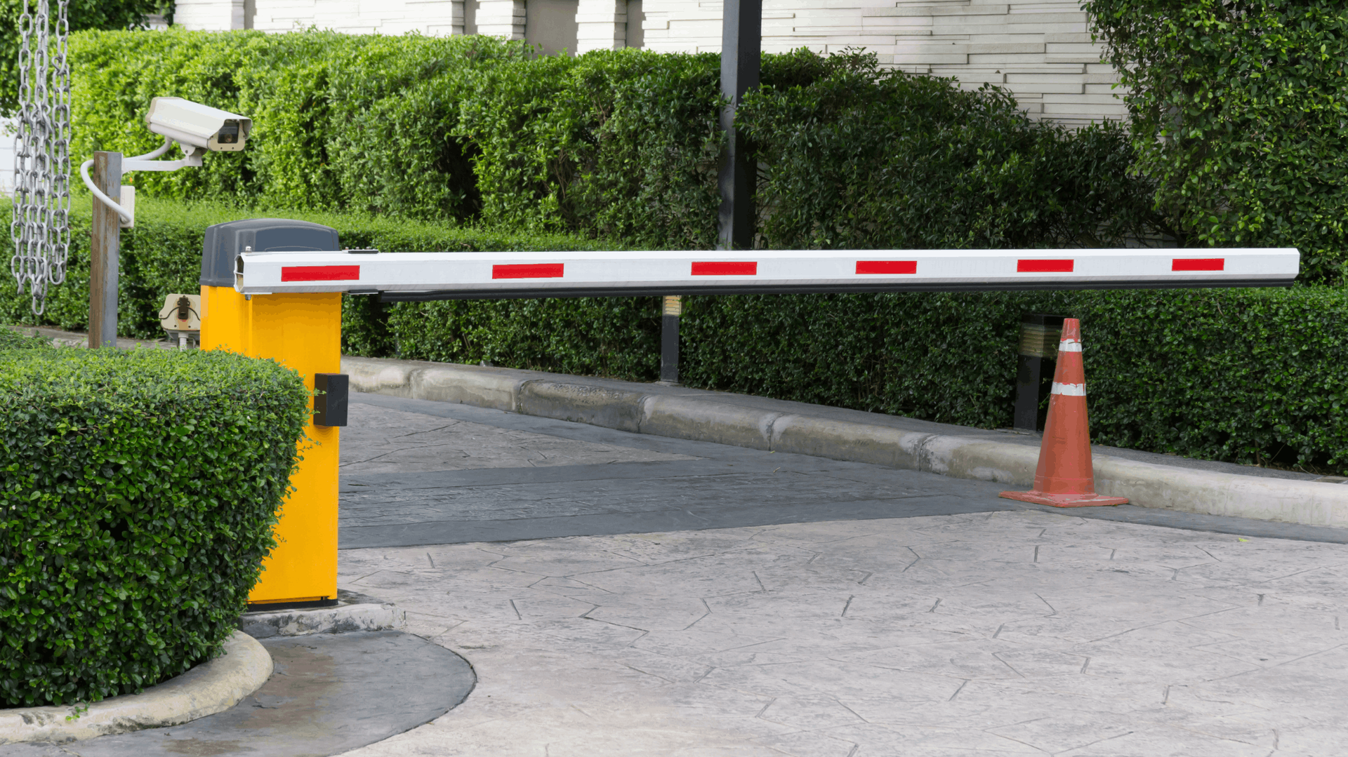 Yellow security gate arm with red stripes raised across a driveway. A security camera and bushes are in the background — Elibon Solutions in Garbutt, QLD