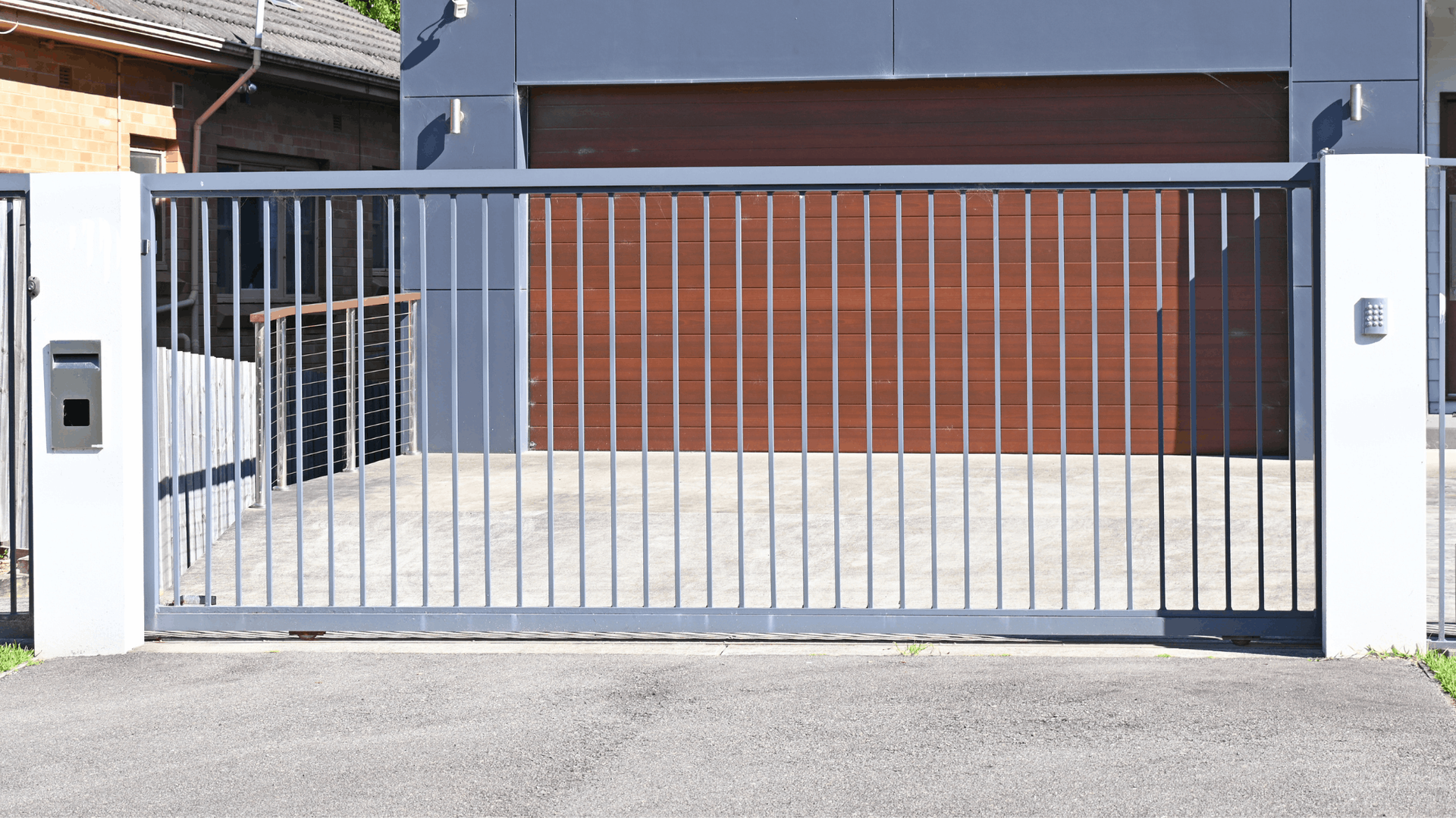 Gray metal sliding gate in front of a modern house, leading to a driveway and garage — Elibon Solutions in Garbutt, QLD