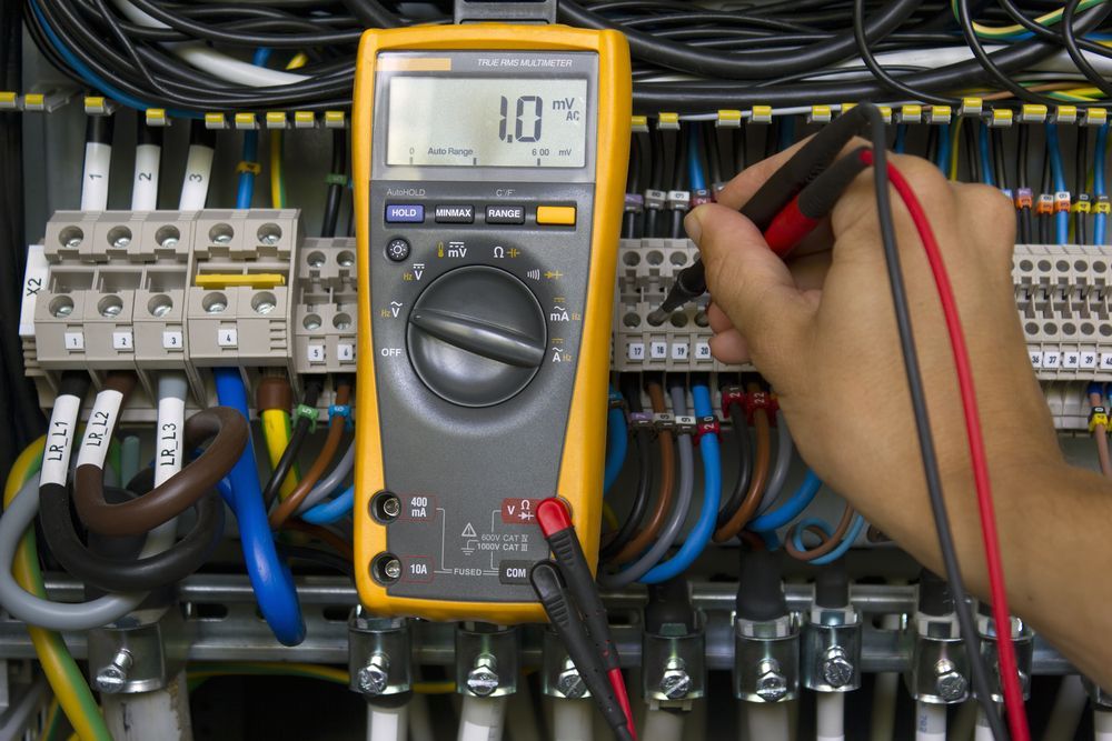 Person Using a Multimeter to Test Electrical Wiring in A Control Panel — Elibon Solutions in Garbutt, QLD