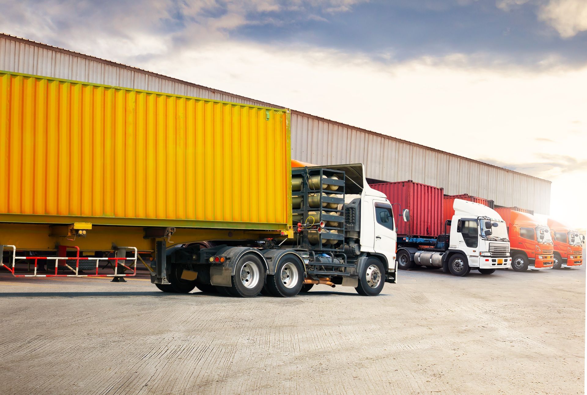 A row of semi trucks parked in front of a warehouse.