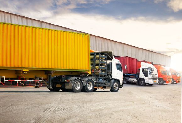 A row of semi trucks parked in front of a warehouse.