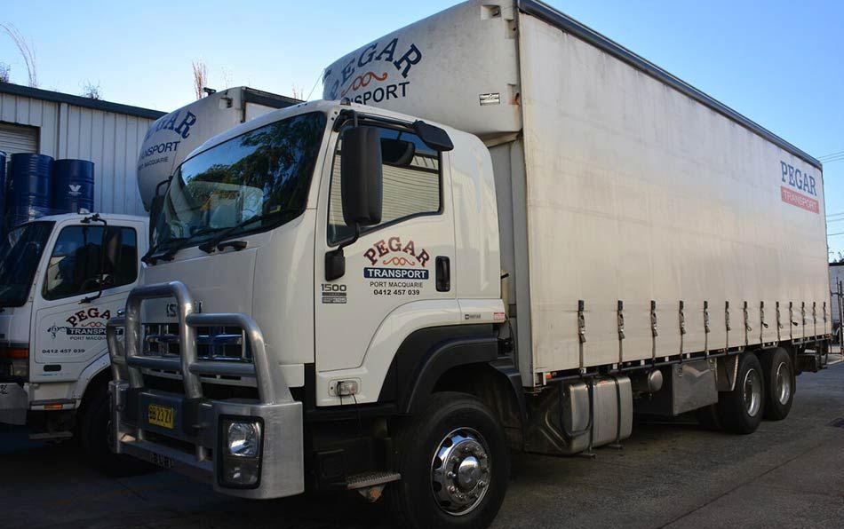 A White Semi Truck Is Driving Down A Highway At Sunset — Pegar Transport In Port Macquarie, NSW