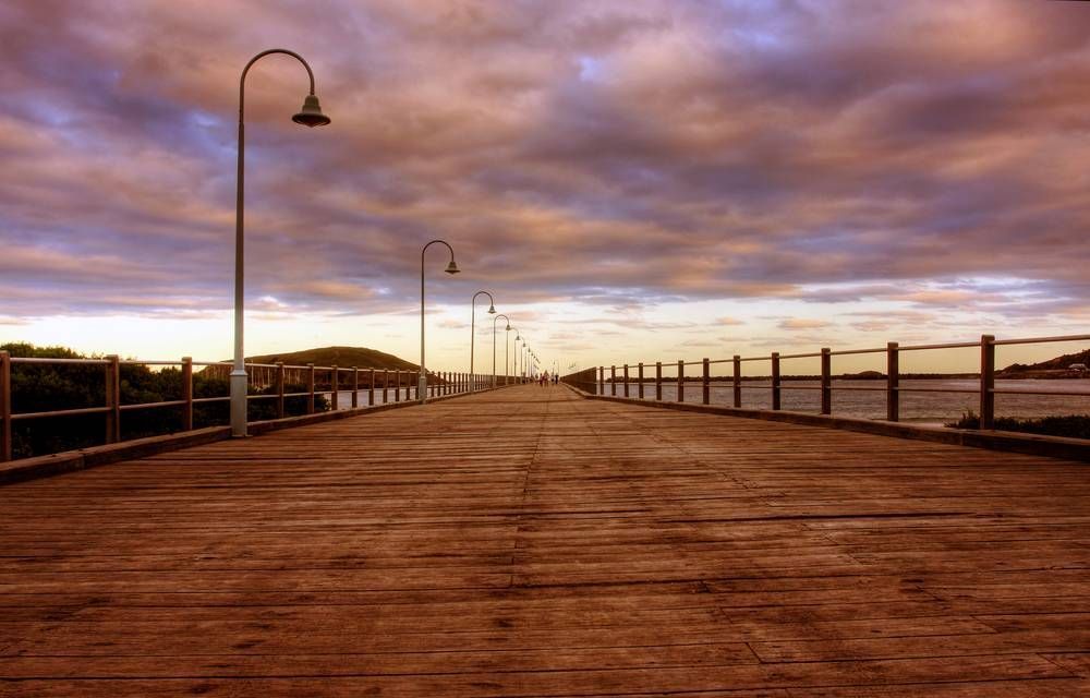 A Wooden Pier With A Sunset In The Background — Pegar Transport In Coffs Harbour, NSW