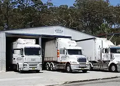 A Row Of Trucks Are Parked In A Parking Lot In Front Of Shipping Containers — Pegar Transport In Coffs Harbour, NSW