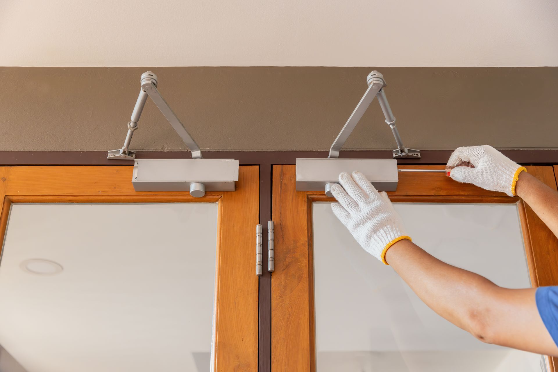 Handyman fixing door closer and adjust hydraulic arm extended.