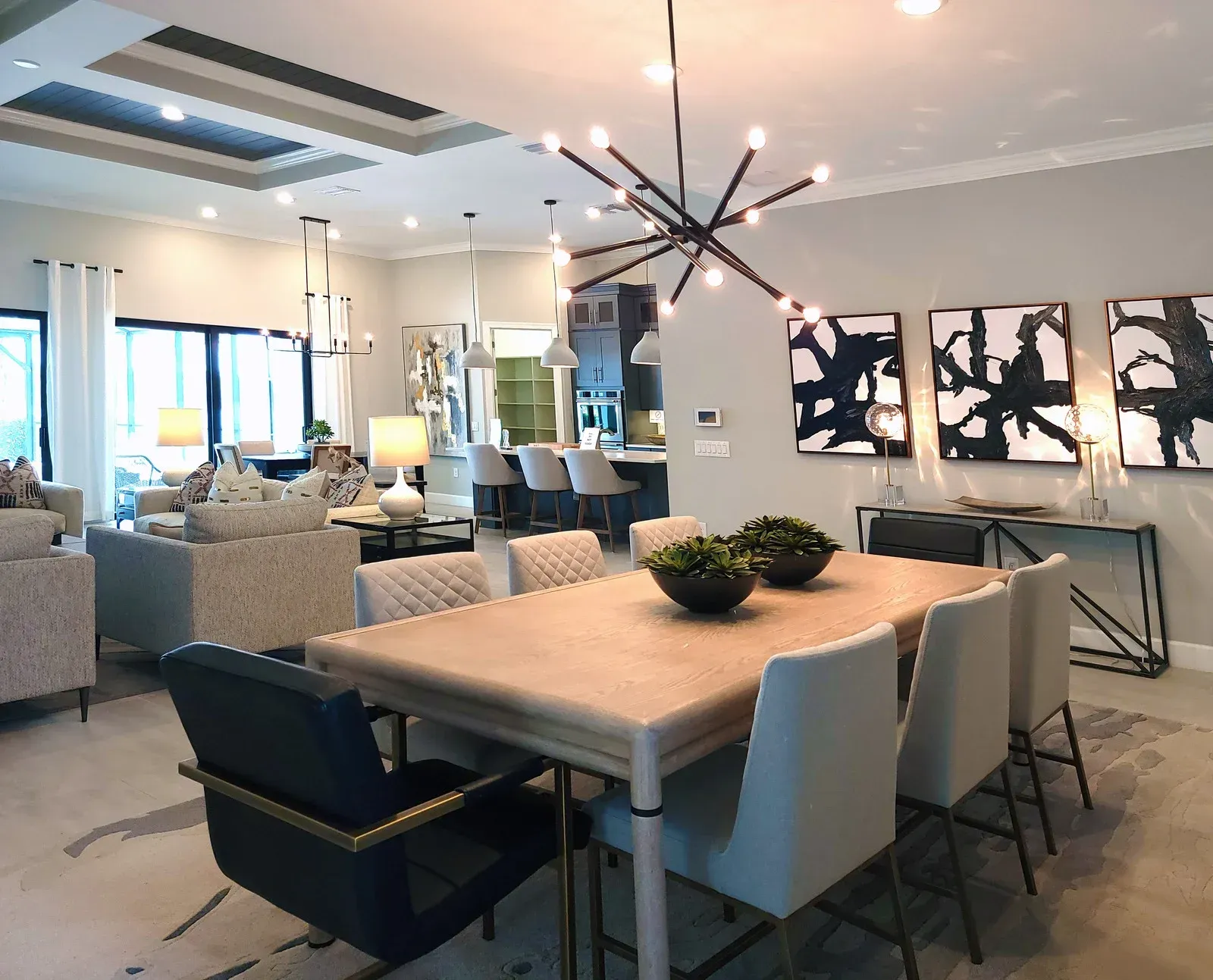 A living room with a dining table and chairs and a chandelier hanging from the ceiling.