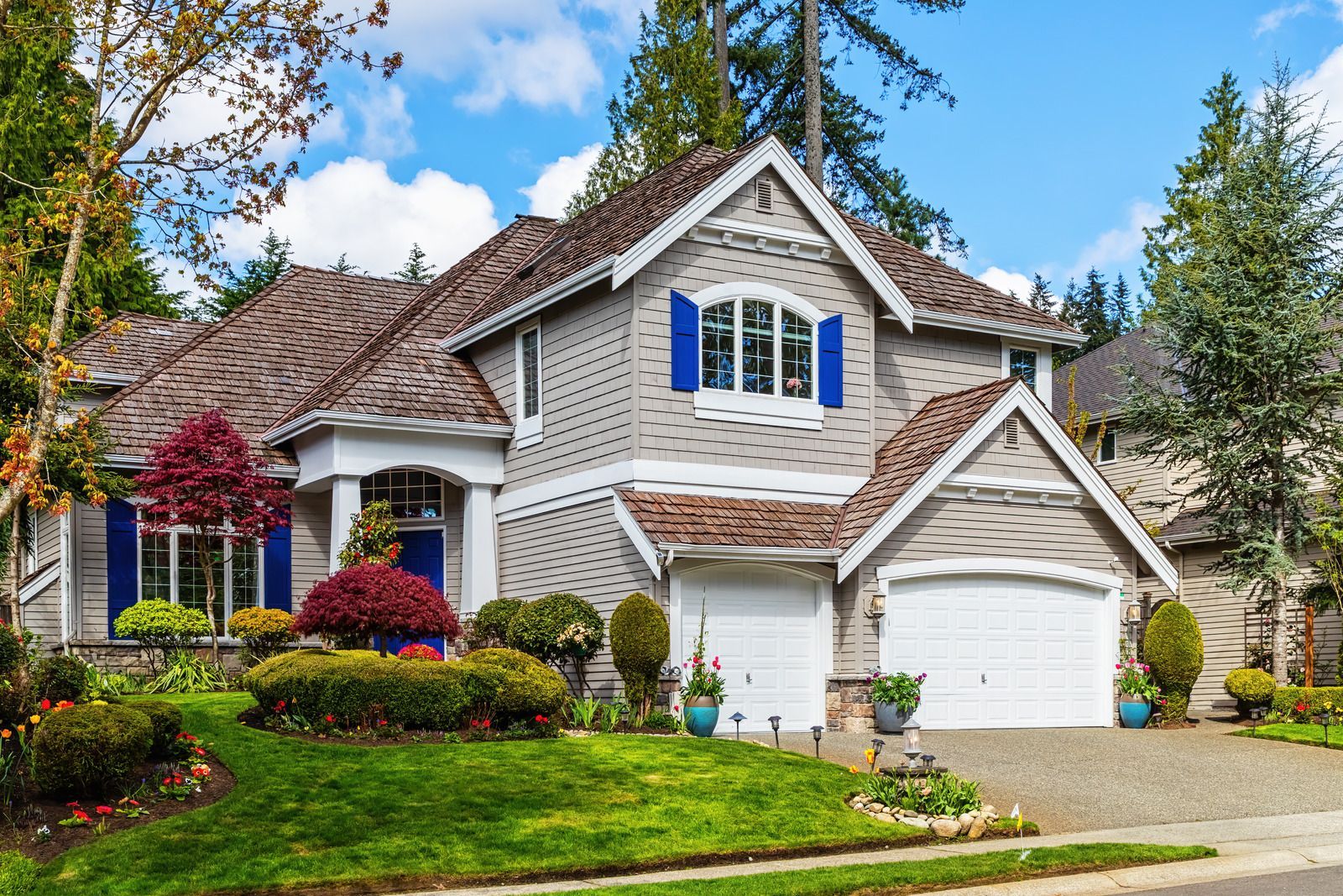 A large house with two garages and blue shutters on the windows.