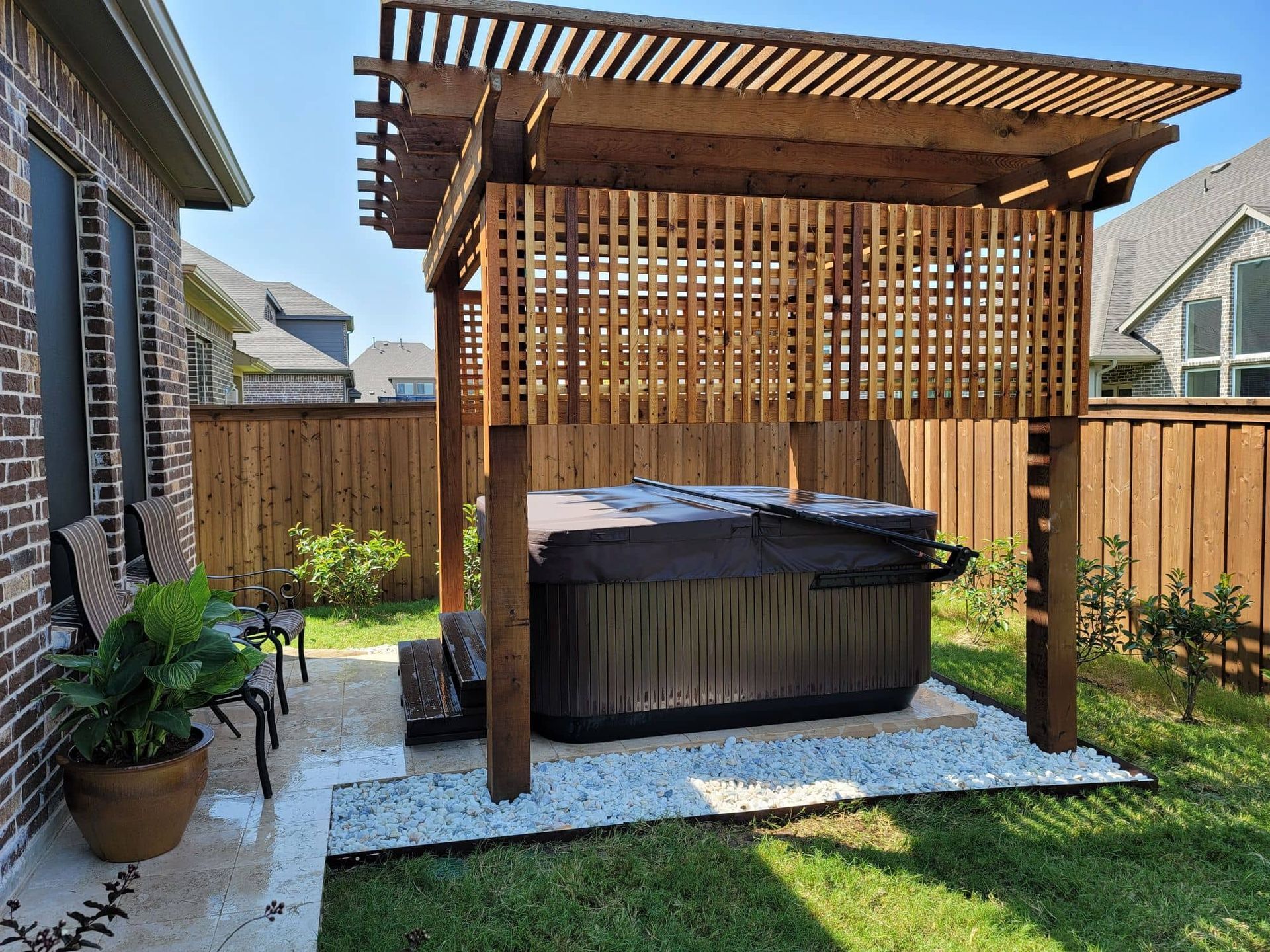 A Hot Tub is under a Wooden Pergola in the Backyard of a House - Tulsa, OK - Outdoor Orchestrators