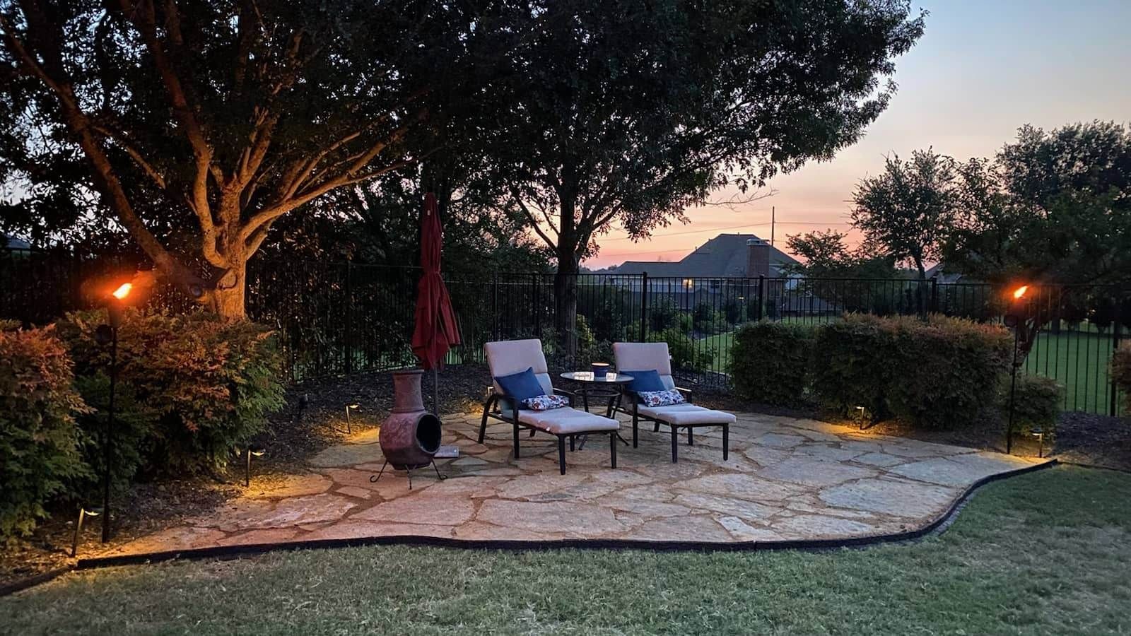 A Patio with Chairs and Umbrellas in a Backyard at Night - Tulsa, OK - Outdoor Orchestrators