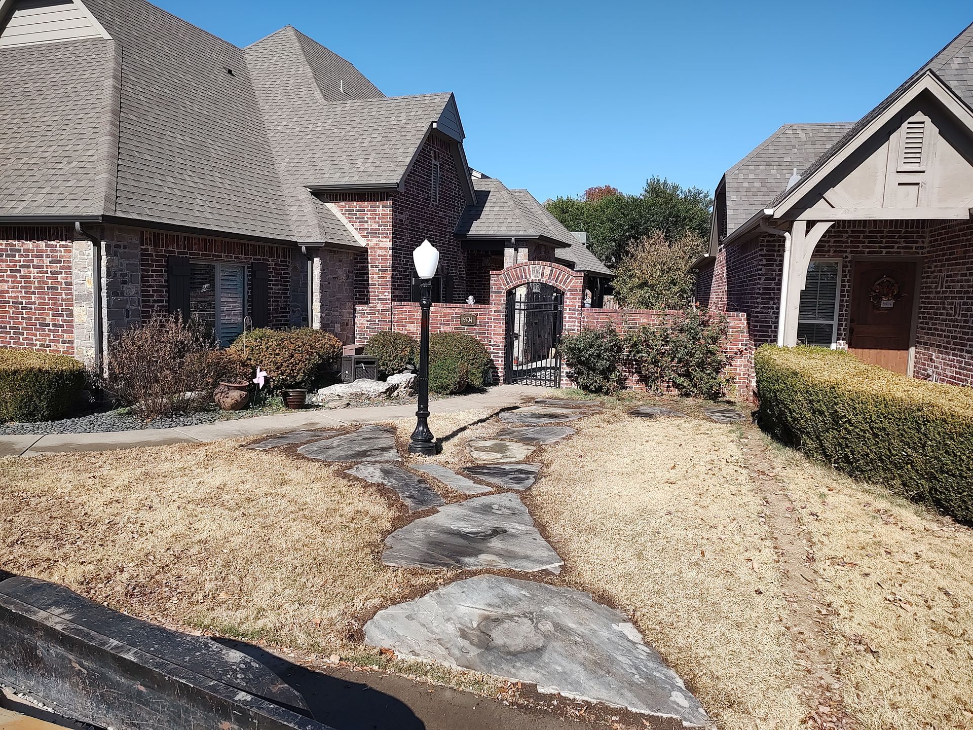Brick townhouses with brown roofs and dry landscaping under a clear blue sky.