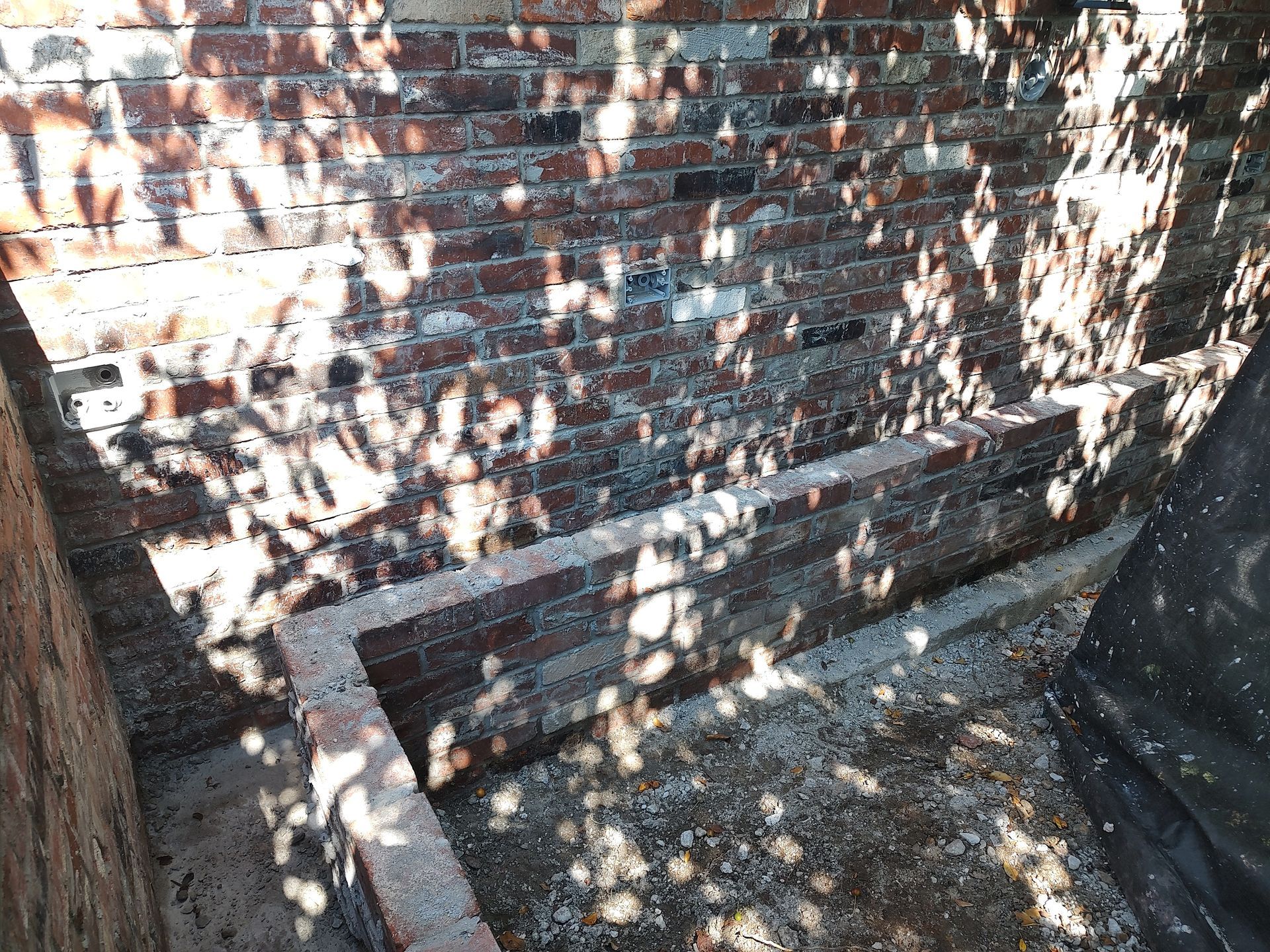 Brick stairs leading down into a shadowed alcove. Sunlight filters through overhead leaves.